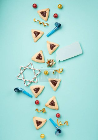 Photo for Homemade Purim hamantaschen cookies, Triangular pastry, Carnival mask, noisemaker, sweet candies and festive party decor on mint green background, Top view. Purim celebration jewish holiday concept. - Royalty Free Image