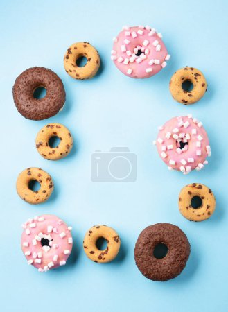 Foto de Donuts doughnuts with chocolate, marshmallow and sugar sprinkles on blue background, copy space. Colorful carnival or birthday party card. Happy National donut day Concept. - Imagen libre de derechos