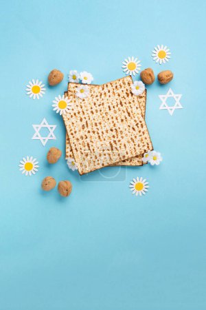 Téléchargez les photos : Carte de vœux de Pâques juive concept avec matzah, noix et fleurs de marguerite sur la table bleue. Seder Pessah printemps fond de vacances, vue de dessus, espace de copie. - en image libre de droit