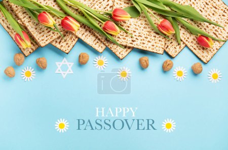 Photo for Jewish holiday Passover greeting card concept with matzah, nuts, tulip and daisy flowers on blue table. Seder Pesach spring holiday background, top view, copy space. - Royalty Free Image