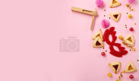Téléchargez les photos : Purim celebration jewish carnival holiday concept. Tasty hamantaschen cookies, Triangular pastry, red carnival mask, noisemaker, sweet candies and party decor on pink background. Top view, flat lay, copy space. - en image libre de droit