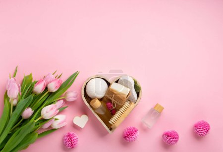 Téléchargez les photos : Natural eco friendly beauty skin care products, spa accessories for women and spring tulip flowers on pink background. Zero waste self care heart shape gift box for mothers day, womans day, birthday. - en image libre de droit