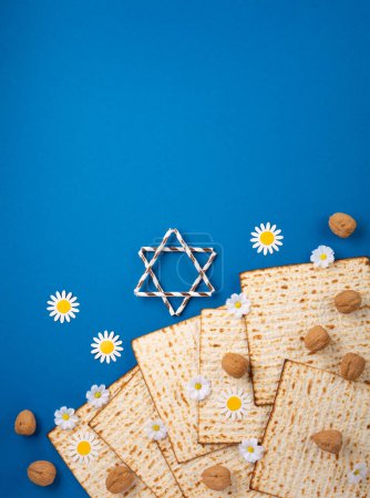 Téléchargez les photos : Noël juif concept de carte de vœux de Pâque avec matzah, noix, fleurs de printemps sur la table bleue. Seder Pessah printemps fond de vacances, vue de dessus, espace de copie. - en image libre de droit