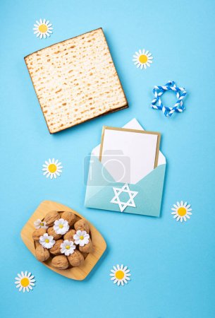 Foto de Fiesta judía concepto de tarjeta de felicitación de Pascua con matzá, nueces, flores de primavera en la mesa azul. Seder Pesach fondo de vacaciones de primavera, vista superior, espacio de copia. - Imagen libre de derechos