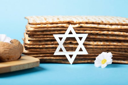 Photo for Jewish holiday Passover greeting card concept with matzah, nuts, spring daisy flowers on blue table. Seder Pesach spring holiday background, copy space. - Royalty Free Image