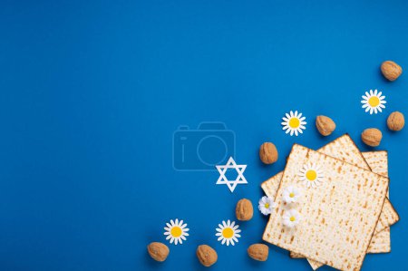 Photo for Jewish holiday Passover greeting card concept with matzah, walnuts, spring daisy flowers on blue table. Seder Pesach spring holiday background, top view, copy space. - Royalty Free Image