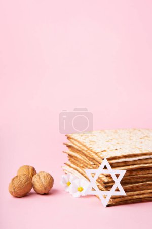 Photo for Jewish holiday Passover greeting card concept with matzah, nuts, spring daisy flowers on pink table. Seder Pesach spring holiday background, copy space. - Royalty Free Image