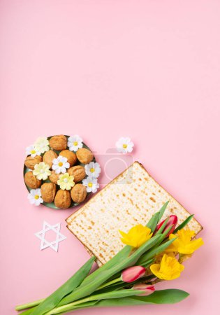 Téléchargez les photos : Noël juif concept de carte de vœux de la Pâque avec matzah, noix, fleurs de marguerite de printemps sur table rose. Seder Pessah printemps fond de vacances, espace de copie. - en image libre de droit