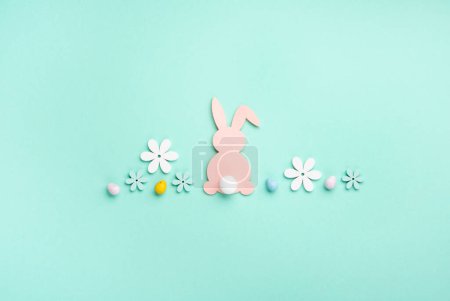 Foto de Pink Easter Bunny, Sweet Colorful Easter Eggs, flores de margarita sobre fondo azul pastel. Feliz Pascua concepto de tarjeta de felicitación, espacio de copia. - Imagen libre de derechos