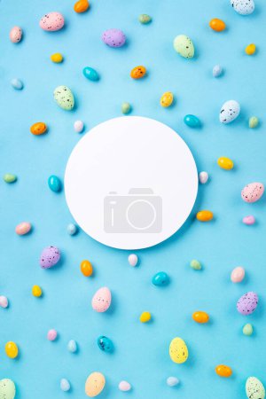 Téléchargez les photos : Oeufs de Pâques colorés doux et fleurs de marguerite blanche sur fond bleu pastel. Joyeux concept de carte de voeux de Pâques. Pose plate, vue du dessus, espace de copie. - en image libre de droit