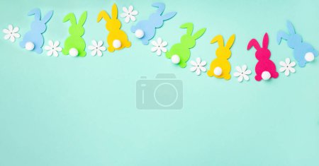 Téléchargez les photos : Lapins de Pâques colorés, oeufs de Pâques colorés doux, fleurs marguerites sur fond de menthe bleu pastel. Joyeux concept de carte de voeux de Pâques, espace de copie. - en image libre de droit