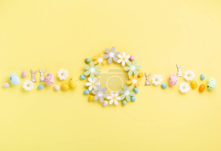 Foto de Dulce colorido huevos de Pascua y flores de margarita blanca primavera sobre fondo amarillo pastel. Feliz Pascua concepto de tarjeta de felicitación. Plano, vista superior, espacio para copiar. - Imagen libre de derechos