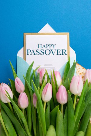 Téléchargez les photos : Noël juif concept de carte de vœux de la Pâque avec matzah, noix, fleurs de tulipes sur table bleue. Seder Pessah printemps fond de vacances, vue de dessus, espace de copie. - en image libre de droit
