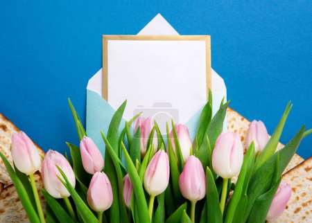 Foto de Fiesta judía concepto de tarjeta de felicitación Pascua con matzá, nueces, flores de tulipán en la mesa azul. Seder Pesach fondo de vacaciones de primavera, vista superior, espacio de copia. - Imagen libre de derechos