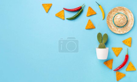 Foto de Fiesta de fondo mexicana con nachos mexicanos tradicionales, chile, cactus y sombrero sobre fondo azul. Concepto de celebración del Cinco de Mayo. Vista superior, espacio de copia. - Imagen libre de derechos