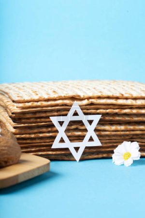 Téléchargez les photos : Jewish holiday Passover greeting card concept with matzah, nuts, spring daisy flowers on blue table. Seder Pesach spring holiday background, copy space. - en image libre de droit