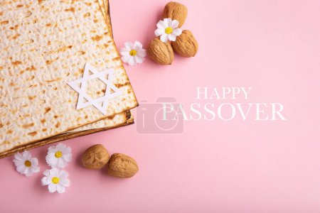 Photo for Jewish holiday Passover greeting card concept with matzah, Star of David, spring daisy flowers, walnuts on pink table. Seder Pesach spring holiday background, copy space. - Royalty Free Image