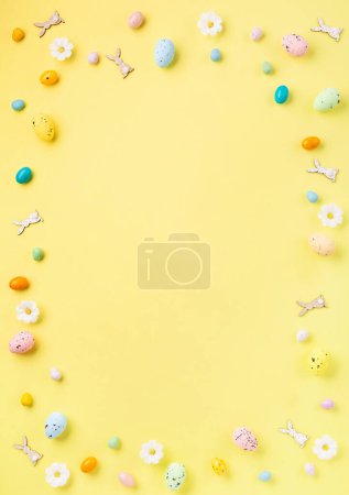 Téléchargez les photos : Oeufs de Pâques colorés doux et fleurs de marguerites blanches de printemps sur fond jaune pastel. Joyeux concept de carte de voeux de Pâques. Pose plate, vue du dessus, espace de copie. - en image libre de droit