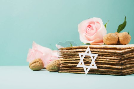 Photo for Jewish holiday Passover greeting card concept with matzah, Star of David, spring flowers, walnuts on blue mint table. Seder Pesach spring holiday background, copy space. - Royalty Free Image