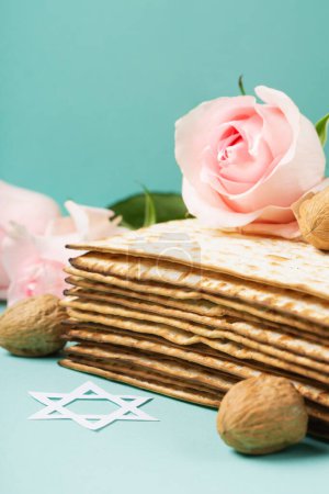 Photo for Jewish holiday Passover greeting card concept with matzah, Star of David, spring flowers, walnuts on blue mint table. Seder Pesach spring holiday background, copy space. - Royalty Free Image