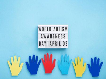 Téléchargez les photos : Journée mondiale de sensibilisation à l'autisme ou concept de mois. Design créatif pour le 2 avril. Mains colorées sur fond bleu, symbole de sensibilisation au trouble du spectre autistique. - en image libre de droit