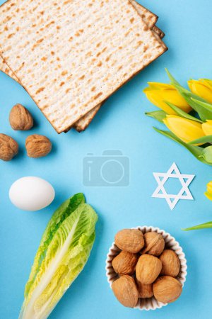 Foto de Fiesta judía concepto de tarjeta de felicitación de Pascua con matzah matzoh (pan de fiesta judía), nueces, flores de tulipán amarillo en la mesa azul. Seder Pesaj fondo de vacaciones de primavera, espacio de copia. - Imagen libre de derechos