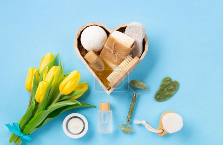 Photo for Natural eco friendly beauty skin care products, spa accessories for women and spring tulip flowers on blue background. Zero waste self care heart shape gift box for Mothers day, womans day, birthday. - Royalty Free Image