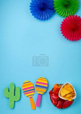 Foto de Fiesta de fondo mexicana con nachos mexicanos tradicionales, chile rojo, cactus y maracas sobre fondo azul. Concepto de celebración del Cinco de Mayo. Vista superior, espacio de copia. - Imagen libre de derechos