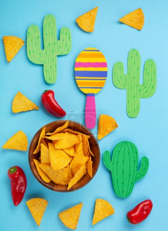 Photo for Mexican background fiesta with Traditional Mexican nachos chips, red chilli pepper, cactus and maracas on blue background. Cinco de Mayo (Fifth of May) celebration concept. Top view, copy space. - Royalty Free Image