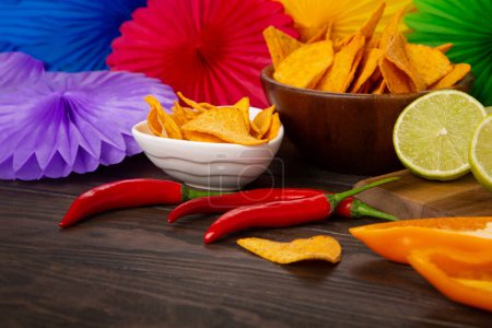 Téléchargez les photos : Cinco de Mayo (Cinquième mai) concept de célébration. Fête d'arrière-plan mexicain avec des copeaux de nachos mexicains traditionnels, piments rouges, citron vert sur fond bois foncé, espace de copie. - en image libre de droit