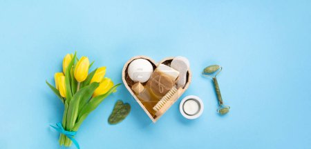 Photo for Natural eco friendly beauty skin care products, spa accessories for women and spring tulip flowers on blue background. Zero waste self care heart shape gift box for Mothers day, womans day, birthday. - Royalty Free Image