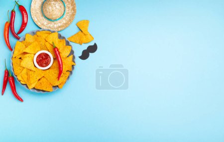 Photo for Mexican fiesta background with Traditional Mexican nachos chips, chilli peppers and tomato salsa sauce on blue table. Cinco de Mayo (Fifth of May) celebration concept. Top view, copy space. - Royalty Free Image