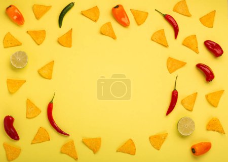 Téléchargez les photos : Fond de la fiesta mexicaine avec des copeaux de nachos mexicains traditionnels, des piments et de la sauce à la salsa de tomate sur fond jaune. Cinco de Mayo (Cinquième mai) concept de célébration. Vue du dessus, espace de copie. - en image libre de droit