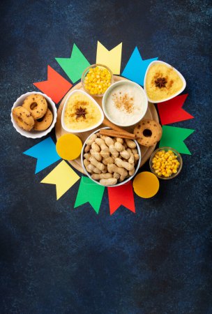 Photo for Festa Junina Summer Festival Carnival concept. Brazilian straw hat, Corn Cakes, peanuts and colorful flags on wooden blue background, top view. Design for Greeting Card, Invitation or Holiday Poster - Royalty Free Image