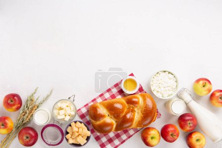 Photo for Happy Shavuot festive card. Jewish religious holiday concept. Dairy products, fresh apples, cheese, bread, milk, cottage cheese, wheat and honey on white background. Top view, copy space. - Royalty Free Image