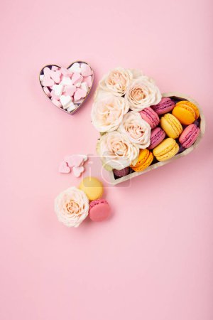 Photo for Sweet cookies macaroons in festive gift box, rose flowers and candies on pink background. Holiday presents concept for Mothers day, womans day valentines day, birthday. Flat lay, empty space for text or message - Royalty Free Image
