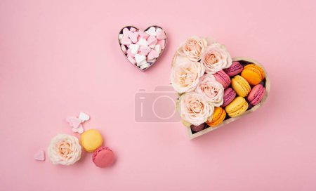 Photo for Sweet cookies macaroons in festive gift box, rose flowers and candies on pink background. Holiday presents concept for Mothers day, womans day valentines day, birthday. Flat lay, empty space for text or message - Royalty Free Image