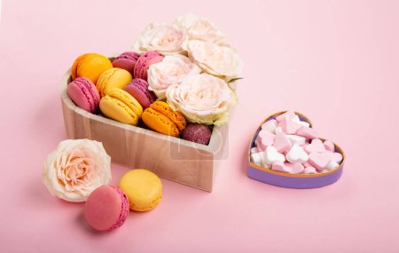 Photo for Sweet cookies macaroons in festive gift box, rose flowers and candies on pink background. Holiday presents concept for Mothers day, womans day valentines day, birthday, empty space for text or message - Royalty Free Image