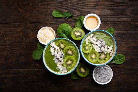 Photo for Green smoothie bowl with organic Spinach, Banana, Chia Seeds, fresh kiwi on dark wooden background. Vegan, Food and drink, healthy dieting and nutrition, alkaline, vegetarian concept. - Royalty Free Image
