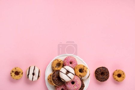 Téléchargez les photos : Donuts colorés vacances beignets avec chocolat et sucre saupoudrer sur fond rose, vue sur le dessus. Carnaval festif ou carte d'anniversaire. Bonne Journée nationale des beignets Concept. - en image libre de droit