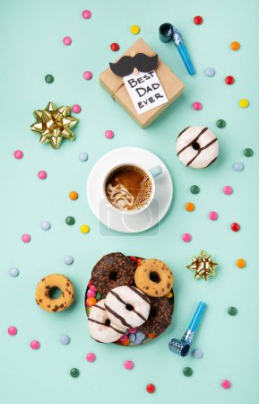 Photo for Fathers day holiday card concept with craft gift box, black moustache, cup of coffee and donuts or doughnuts on blue mint background, top view, copy space. - Royalty Free Image