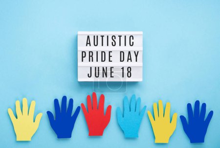 Téléchargez les photos : Journée de la fierté autistique ou concept de Journée mondiale de sensibilisation à l'autisme. Design créatif pour le 18 juin. Mains colorées sur fond bleu, symbole de sensibilisation au trouble du spectre autistique. - en image libre de droit