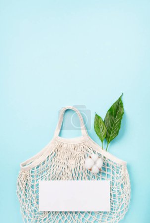 Téléchargez les photos : International sac en plastique concept de journée libre. Style de vie durable et écologique. Dis non au plastique. Vas-y vert. Sauver la nature. Sac en maille de coton textile réutilisable et recyclable et fleur sur fond bleu - en image libre de droit
