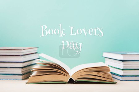 Photo for Book Lovers Day, Education concept. Open Book on wooden table and Stack of books on blue mint background. Festive card for books holiday, copy space. - Royalty Free Image