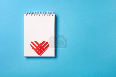 Photo for Giving Tuesday, global day of charitable giving after Black Friday shopping day. Charity, give help, donations support concept. Red paper heart and empty white notepad on blue background. Top view, copy space, flat lay. - Royalty Free Image