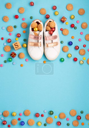 Photo for Saint Nicholas Day, 6 December. Christmas card with children's shoes, sweets, candy, gingerbread cookies, gifts on blue table. Traditional Sinterklaas, Saint Nicholas day background, winter holiday in Germany and Western Europe. - Royalty Free Image