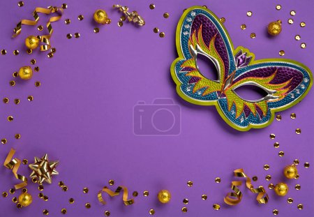 Foto de Mardi Gras masquerade festival carnival mask, sweet chocolate candies, gold beads and golden confetti on purple background. Holiday party invitation, greeting card concept, cope space - Imagen libre de derechos