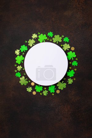 Téléchargez les photos : St. Patrick's Day celebration Concept. Greeting card with traditional symbols - Golden horseshoe, gold coins and clover leaves, green shamrocks on dark brown wooden background. Top view, copy space. - en image libre de droit