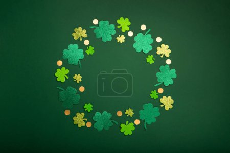 Téléchargez les photos : Carte de jour St Patricks avec symboles traditionnels pour fête irlandaise. Fer à cheval doré, pièces d'or, feuilles de trèfle, trèfles verts sur fond vert. Vue de dessus. Concept de célébration de la Saint-Patrick. - en image libre de droit