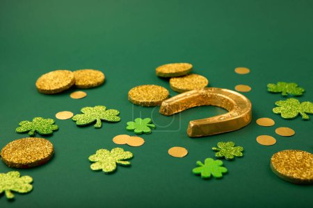 Photo for St Patricks day card with traditional symbols for irish party. Golden horseshoe, gold coins, clover leaves, green shamrocks on green background, copy space. St. Patrick's Day celebration concept. - Royalty Free Image